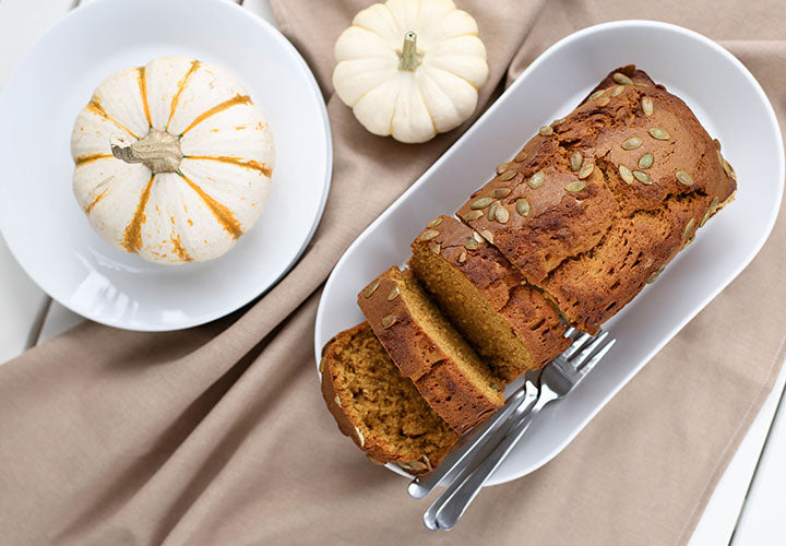 Loaf of sweet pumpkin bread garnished with pumpkin seeds.