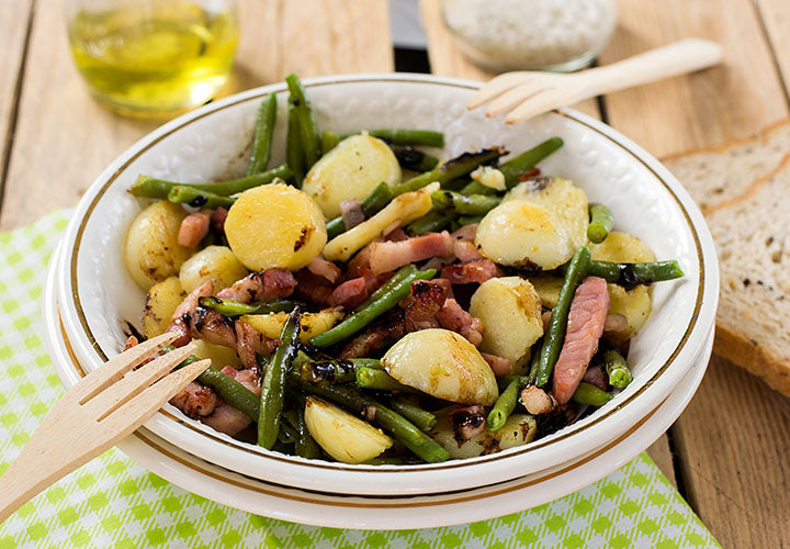 Potato salad served warm with bacon and green beans.