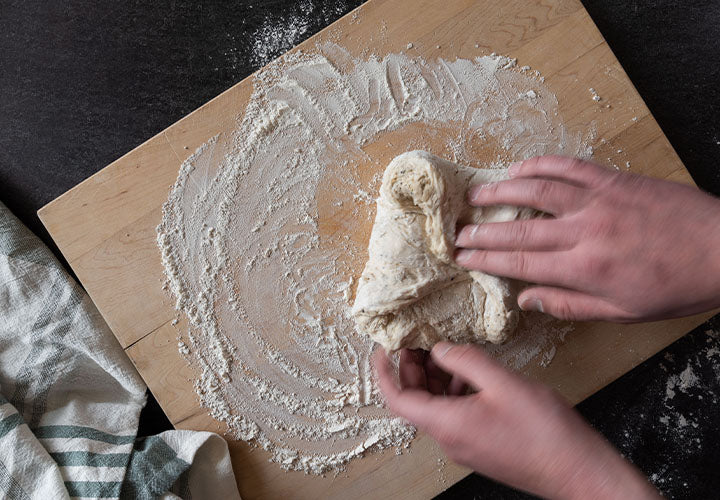Lightly pressing dough on floured surface