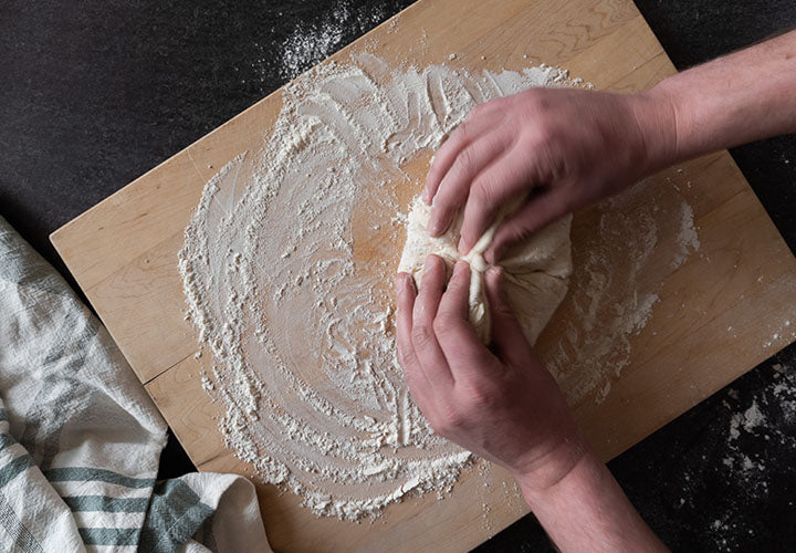 Spinning dough into a ball on floured surface