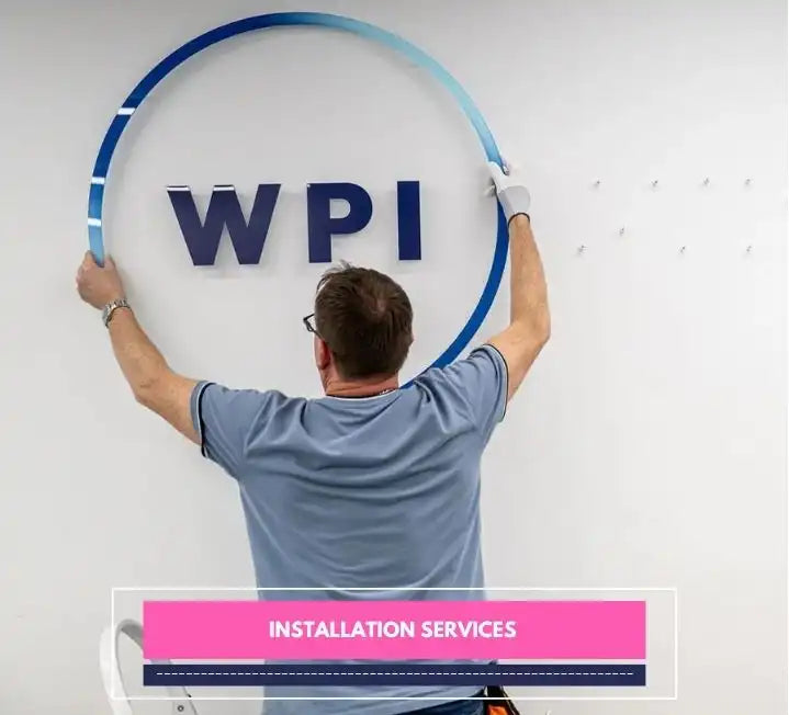 Worker installing a wall-mounted company logo sign as part of installation services.