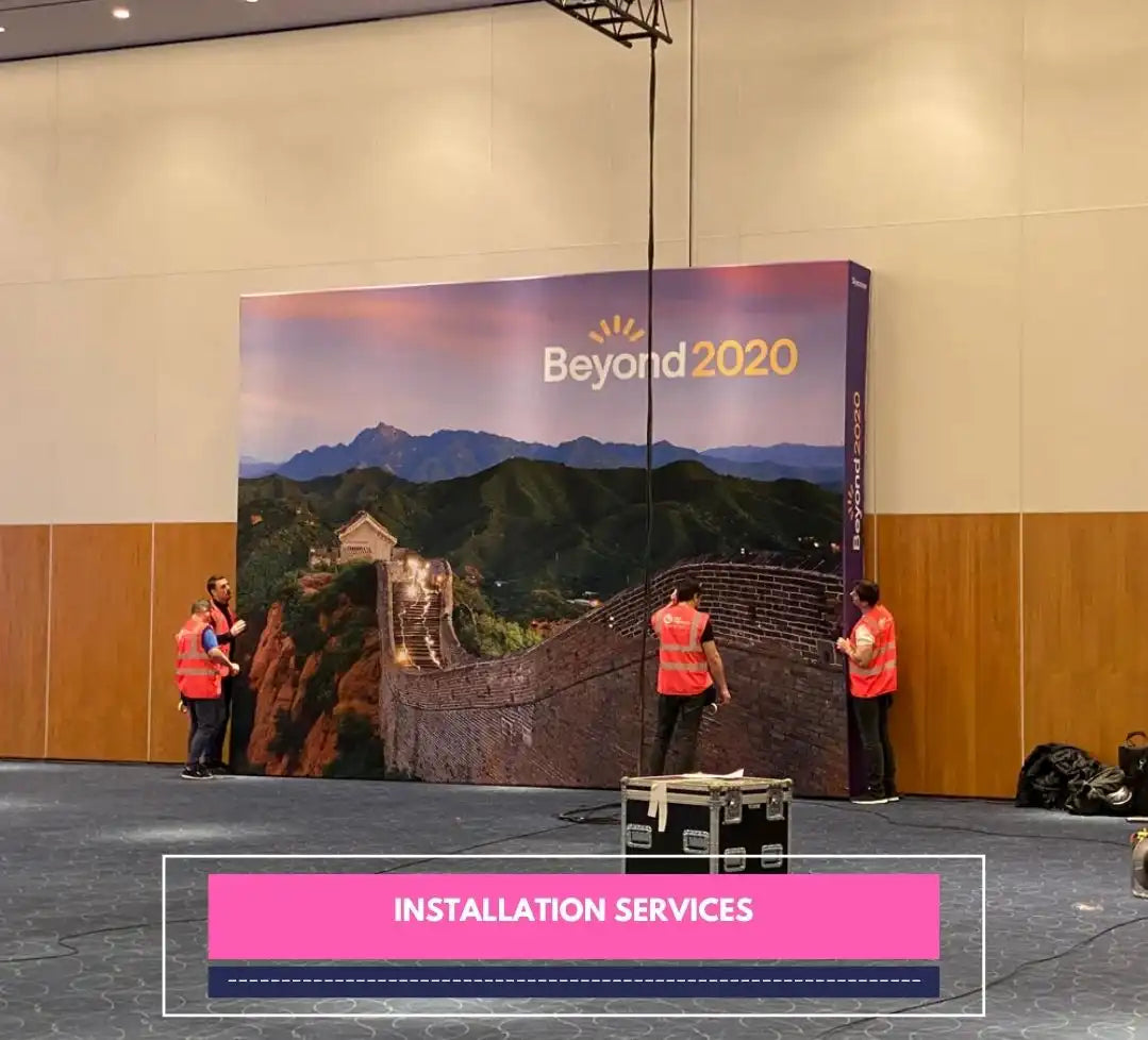 Team installing a large "Beyond 2020" Great Wall backdrop at indoor event