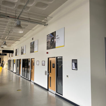 Modern office hallway with glass doors, wall-mounted posters, and a clean design layout.