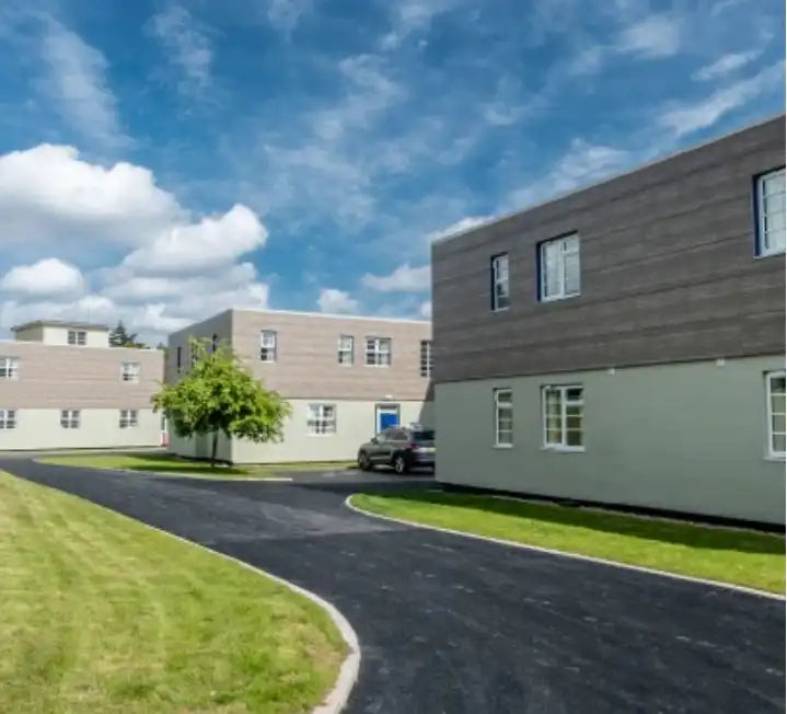 Exterior view of St Marthas care home with modern buildings and landscaped path.