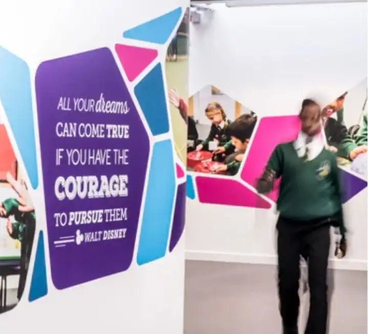 School hallway mural with Walt Disney quote and students in green uniforms walking past.