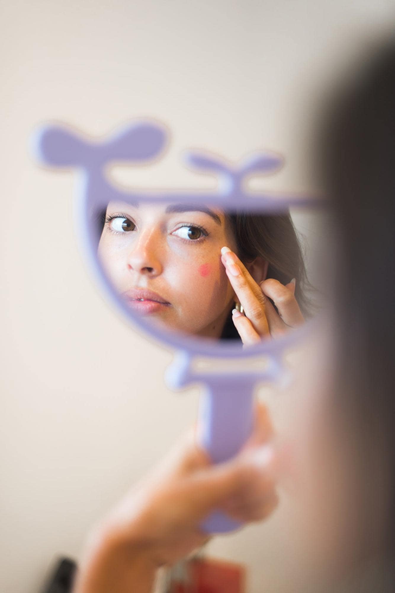 person looking in whale mirror putting on makeup