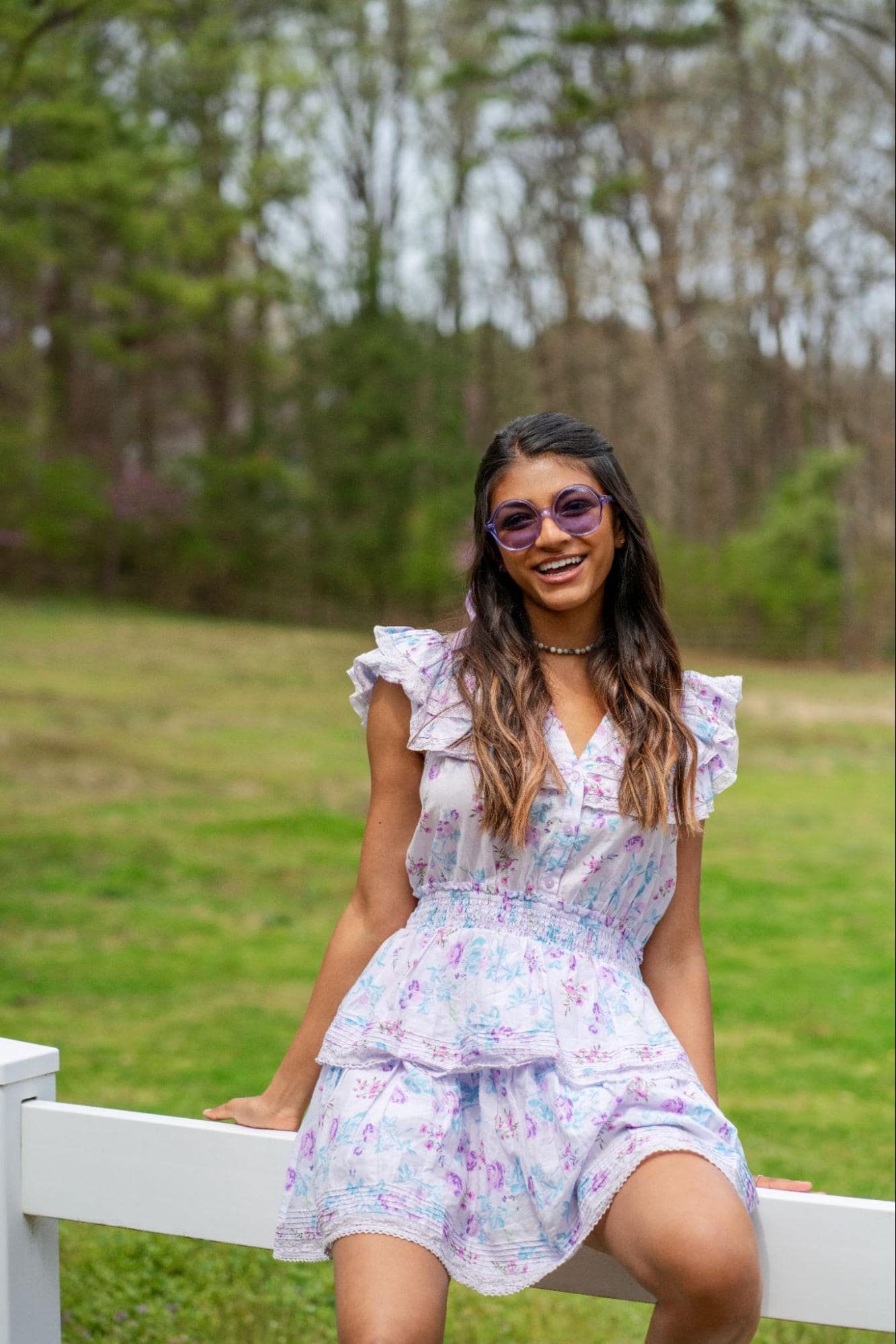 Person half-sitting on fence in floral dress