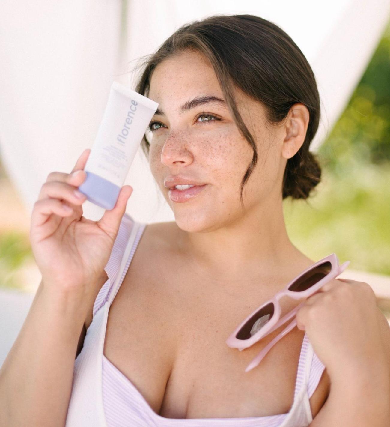 Girl holding up a bottle of sunscreen