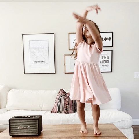 little girl dancing in pink twirl dress on coffee table