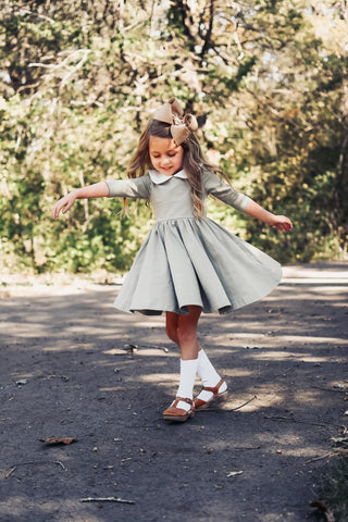 girl twirling in a green dress and bow during fall