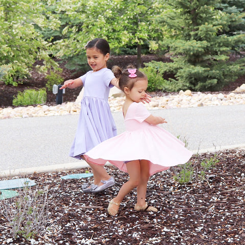 little girl twirling in pink dress and little girl in lavender twirl dress