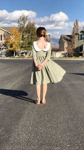 seven year old girl standing in street modeling her green dress with scoop back