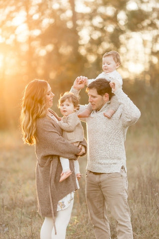 mom dad and 2 kids in field of golden light for family holiday photo