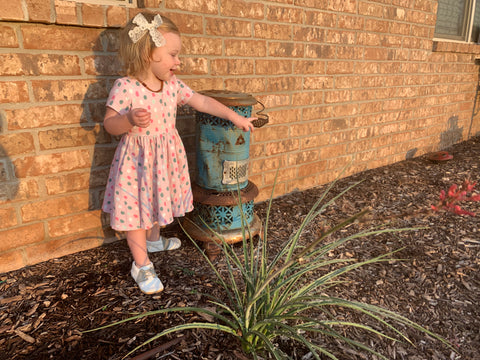 young girl in ollie jay dots twirl dress standing in front of brick wall
