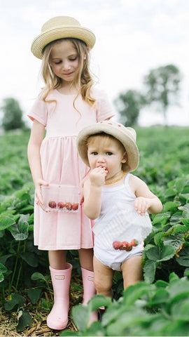 young girl in pink dress and baby at strawberry field
