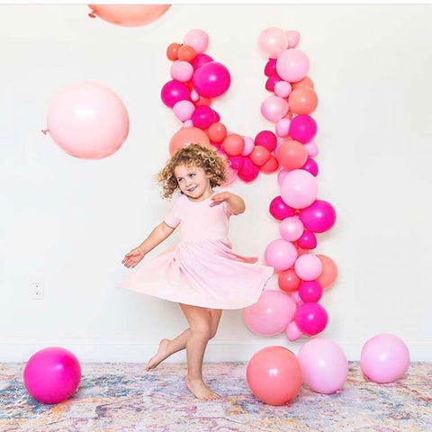 curly haired girl dancing in twirl dress in front of balloon collage that shows number four