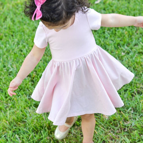girl standing on grass in pink twirling dress