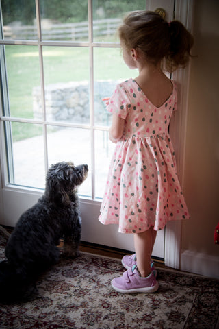 girl and dog standing at door looking out window