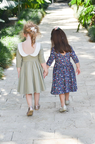 two toddler friends walking down a path holding hands