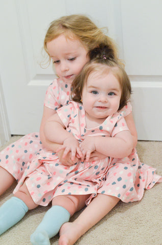baby and toddler in matching dresses smiling