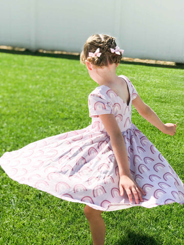 girl in braided pigtail look, twirling in ollie jay dress on grass