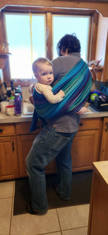 Customer photo of dad carrying child in a long woven wrap in print Promenade