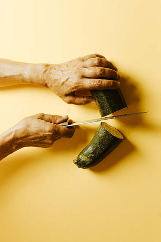 Hands cutting zucchini with a knife