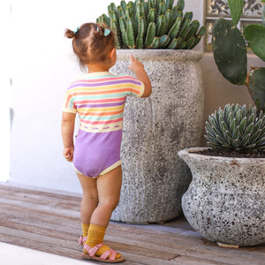 Cute baby girl outside in rainbow coloured romper