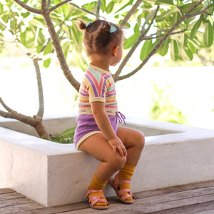 Cute baby girl outside in rainbow coloured romper