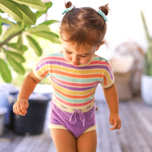 Cute baby girl outside in rainbow coloured romper