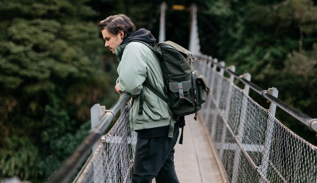 Man on a bridge wearing a camera backpack