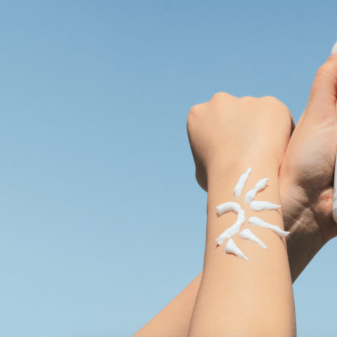 white cream applied to arm in the shape of a sun with blue sky background