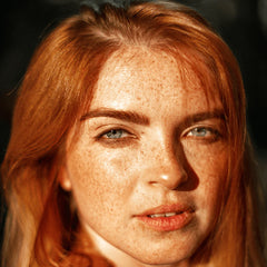 woman with red hair and freckles with sun on her face
