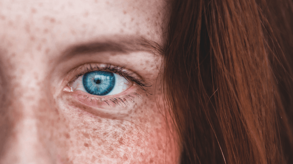 woman's blue eye with red hair and freckles