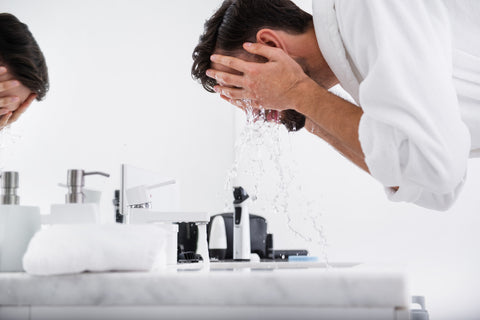 man splashing water on face