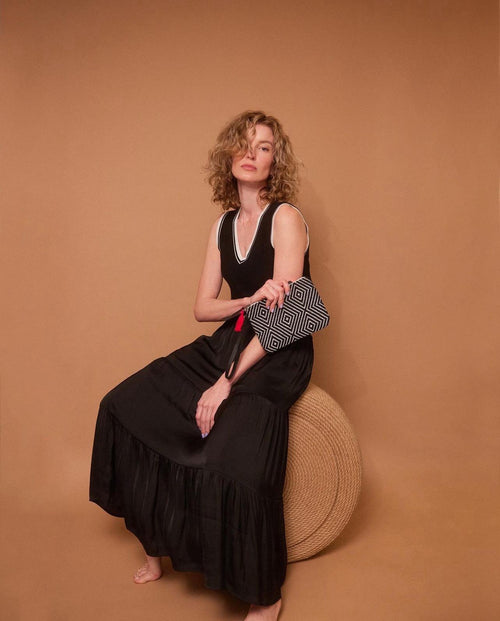 Model sitting down holding hand woven artisan Mini Lily Wristlet