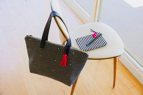 Liverpool Hand Woven Artisan bag draped on a chair with a striped handbag