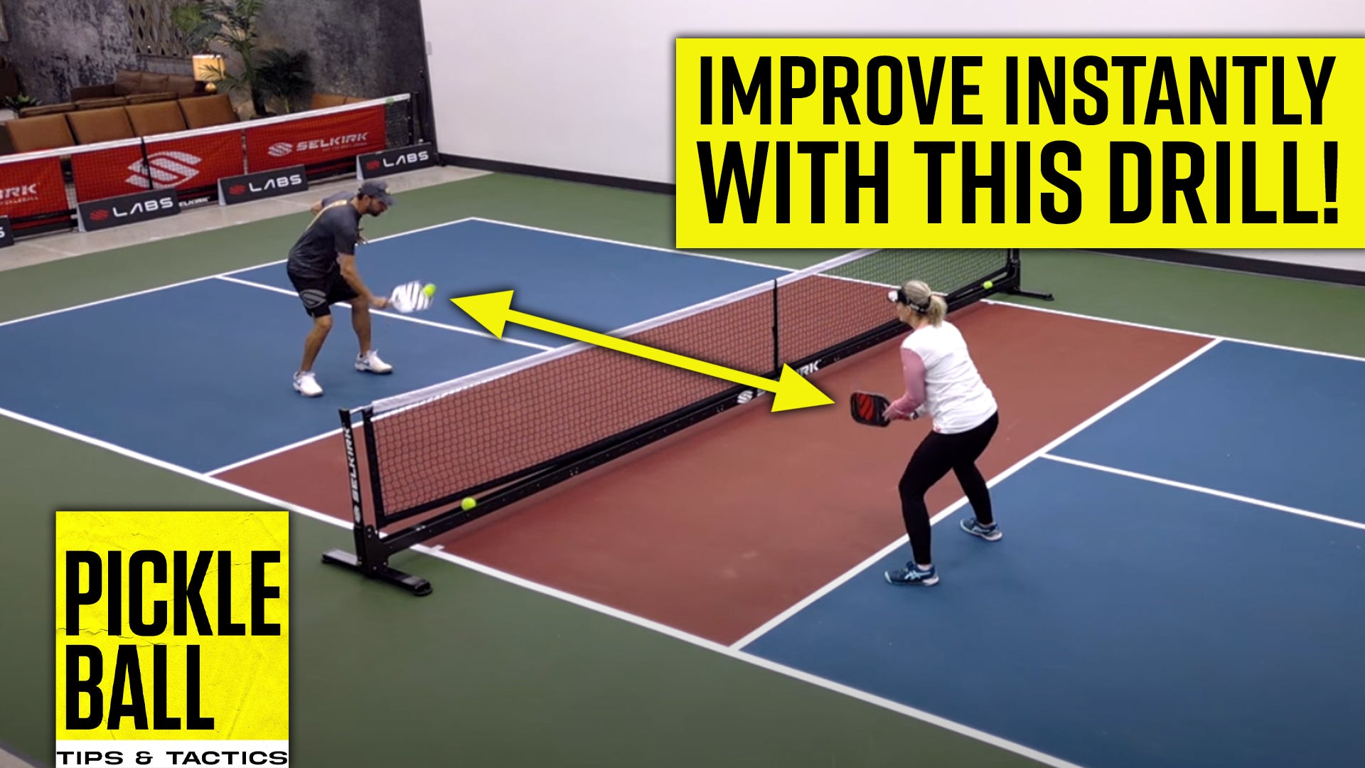 Professional pickleball coach DJ and a woman stand on an indoor pickleball court. He hits a volley out of the air while the woman waits to receive the ball at the kitchen line.