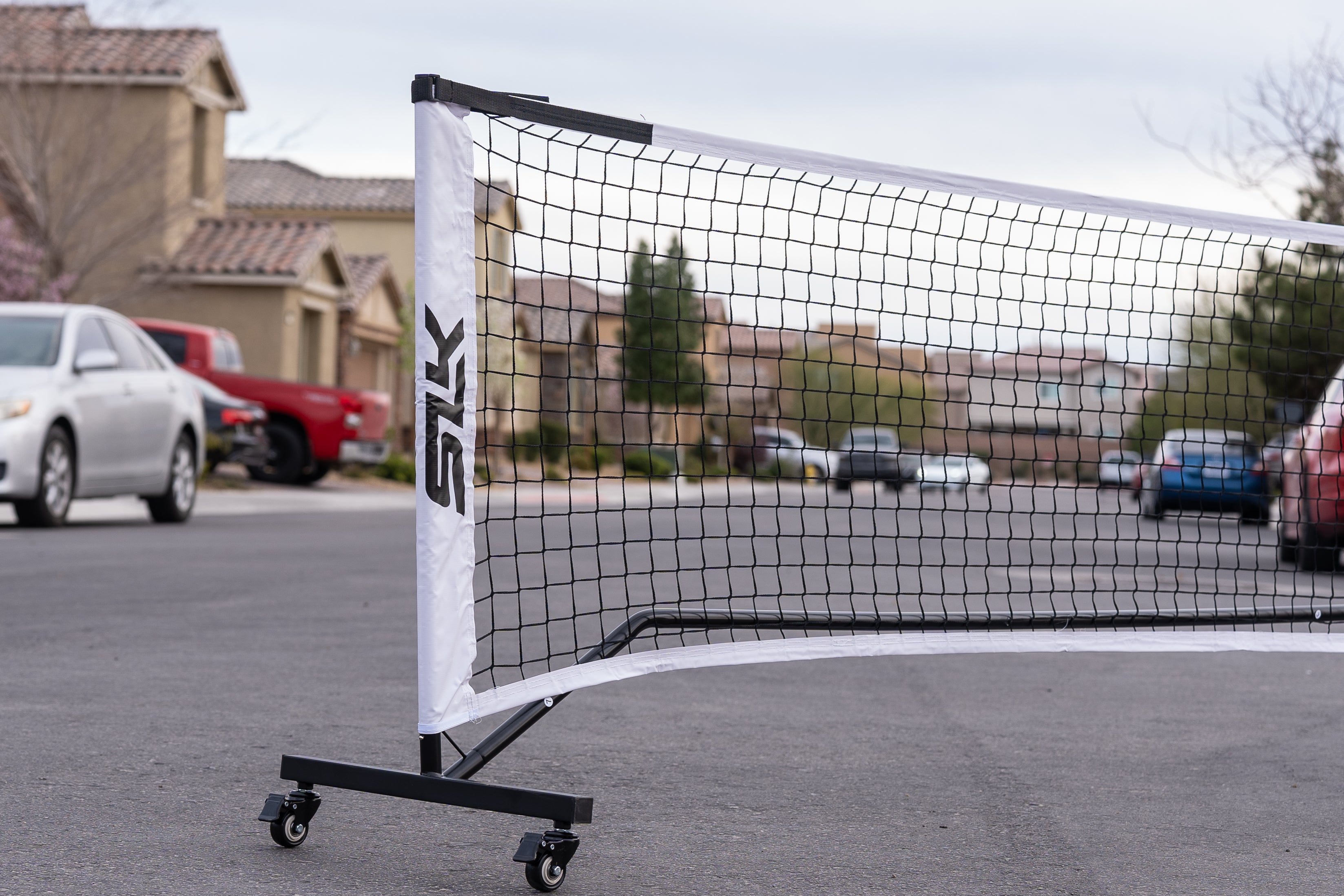 A portable SLK net with wheels sits at the end of a cul-de-sac street, presumably to be used on a make-shift court.