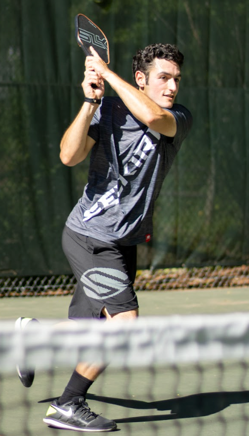 Noah Zwiren executes a backhand shot with his SLK Halo near the net on the pickleball court.