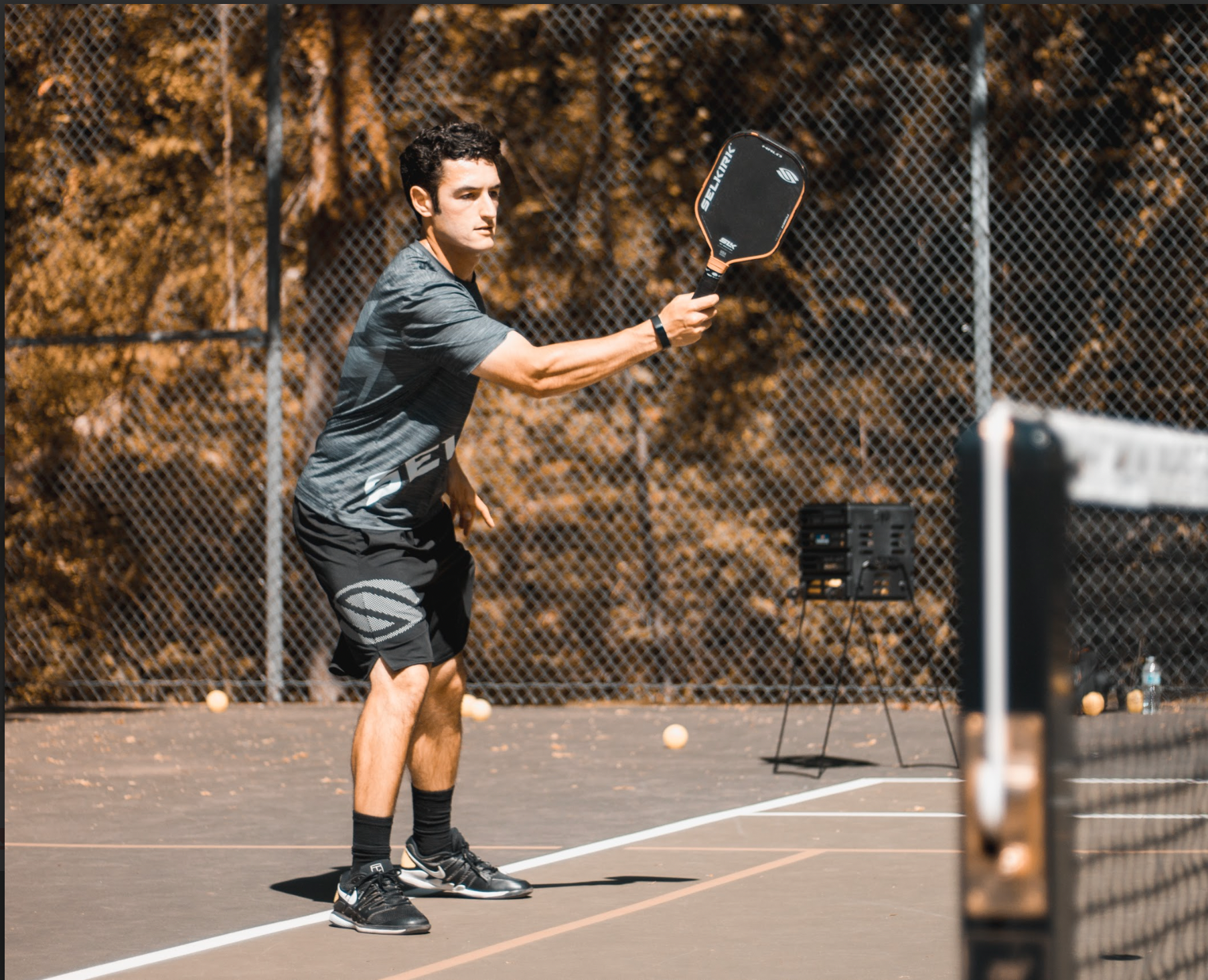 Noah Zwiren stands on a pickleball court at the kitchen line. He is holding his SLK Halo out in front of his body in a ready position.