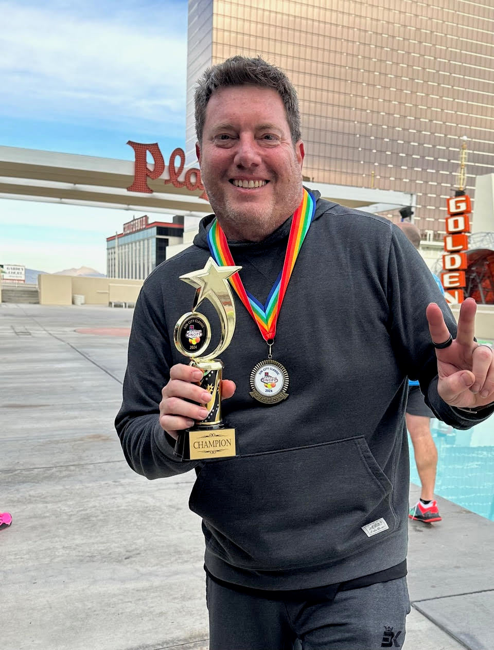 Jonathan Stone holds up a trophy in Las Vegas. He has a gold medal and is smiling at the camera.
