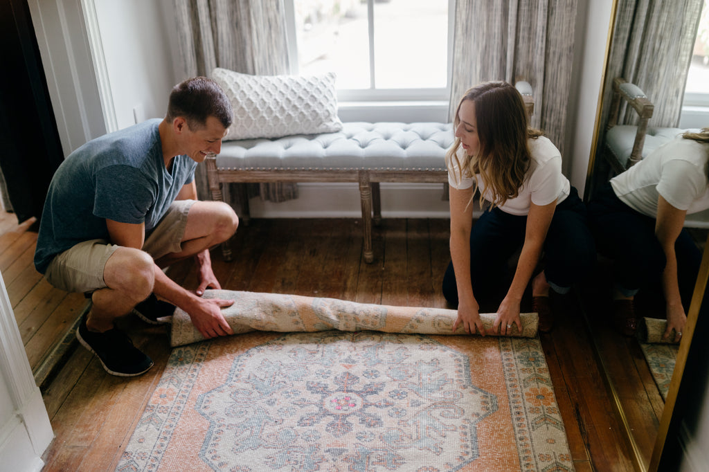Brett and Heather roll up a large vintage rug together.