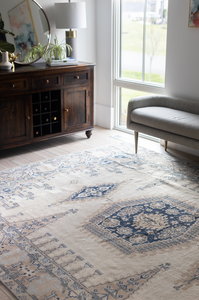 A cream and blue vintage rug styled in a bedroom.