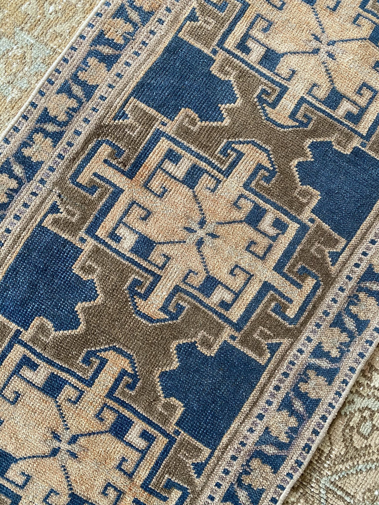 A tiny Turkish rug in a blue and brown colorway.