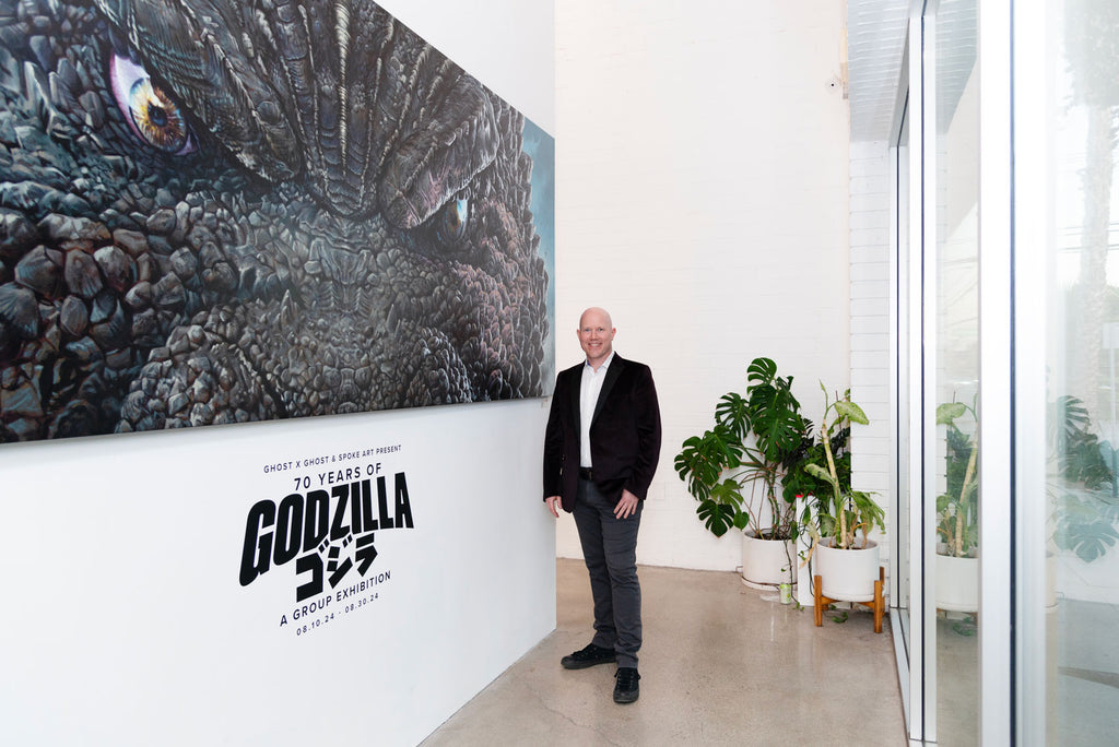 Artist Jason Edmiston next to his painting at the 70 Years of Godzilla opening reception in Los Angeles