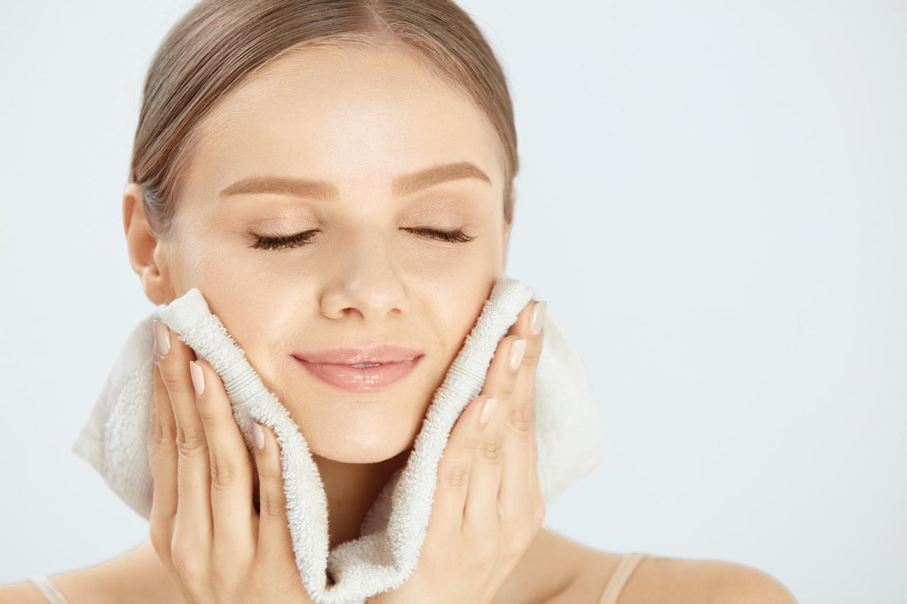 a woman cleaning her face with washcloth, white washcloth