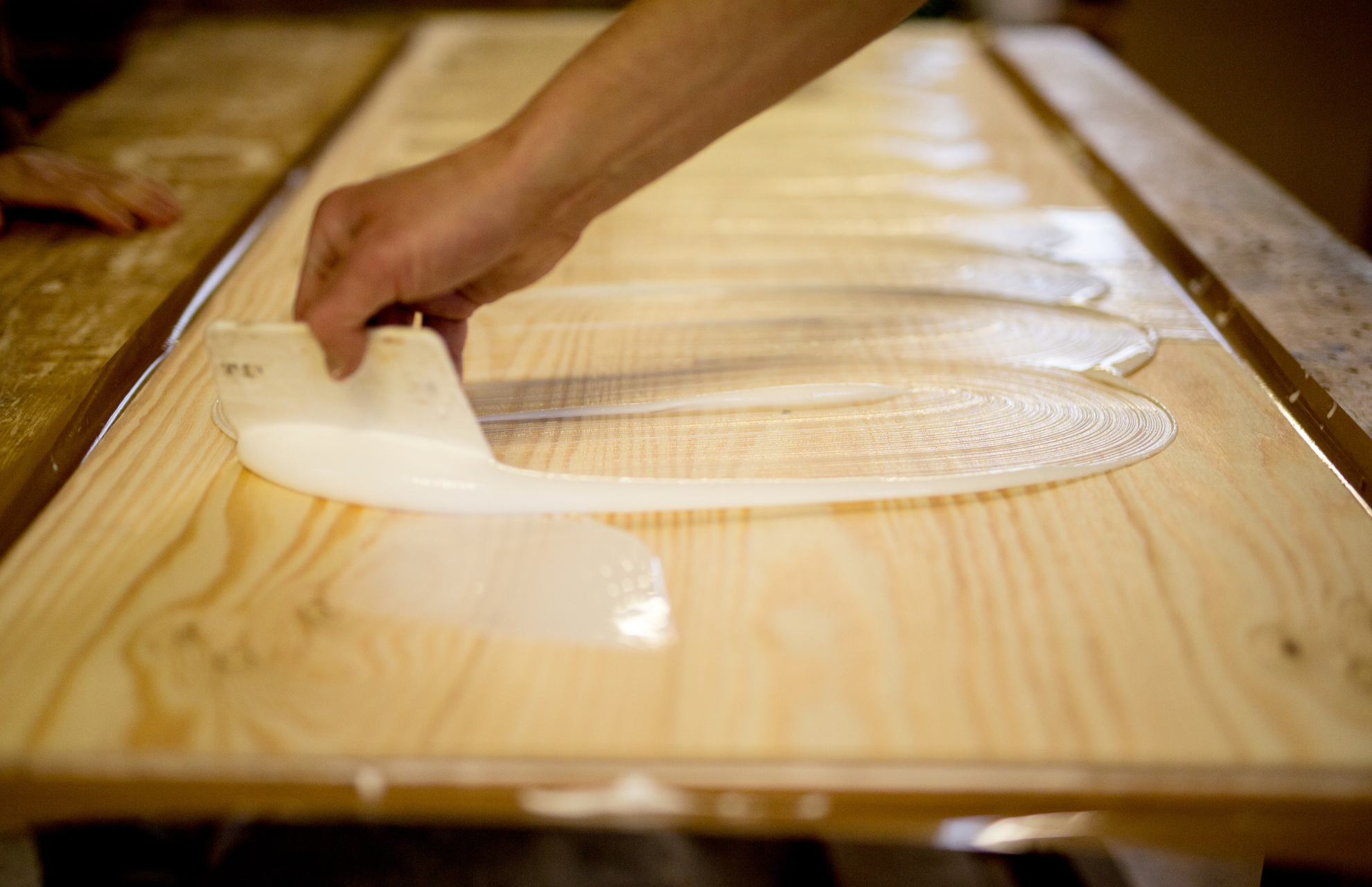 Person applying a thick layer of glue onto a wood tabletop