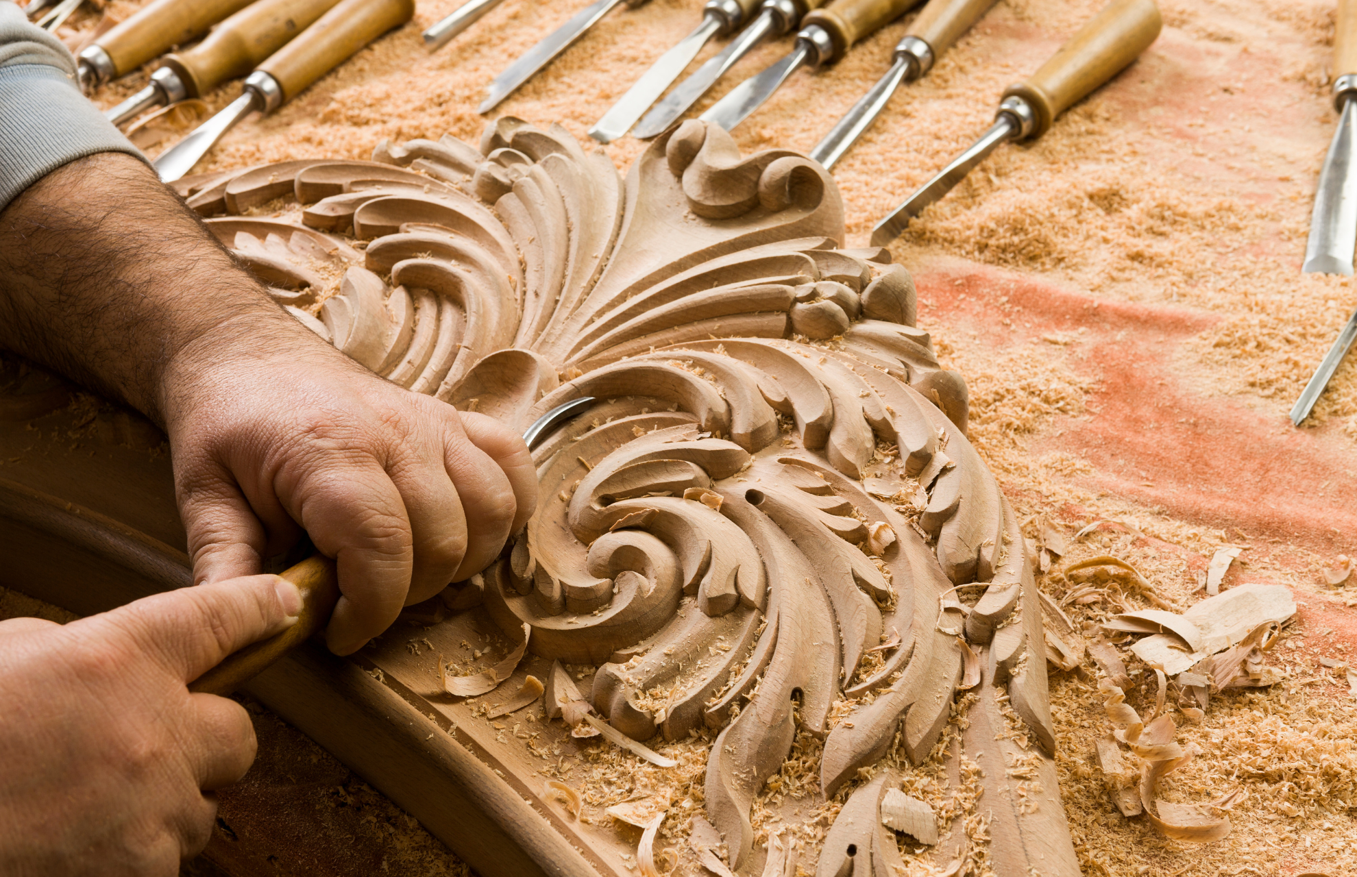 Person carving intricate details to manufactured wood