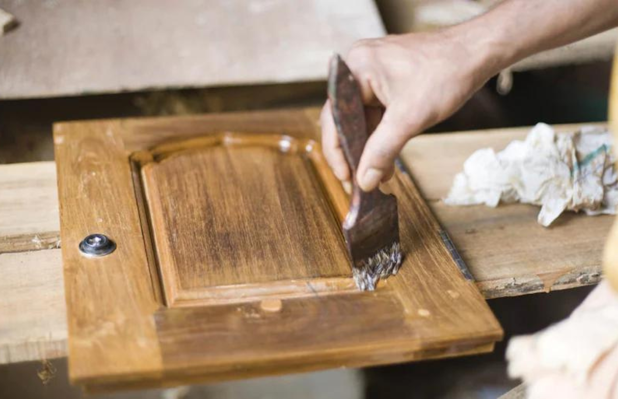 Person applying sealant onto wooden cabinet door